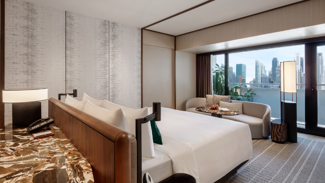Luxurious hotel room with a king-size bed, offering views of the city skyline from your balcony with floor-to-ceiling windows and modern furnishings.