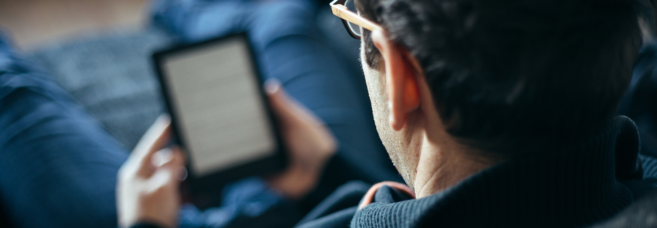 man reading from a device on couch 